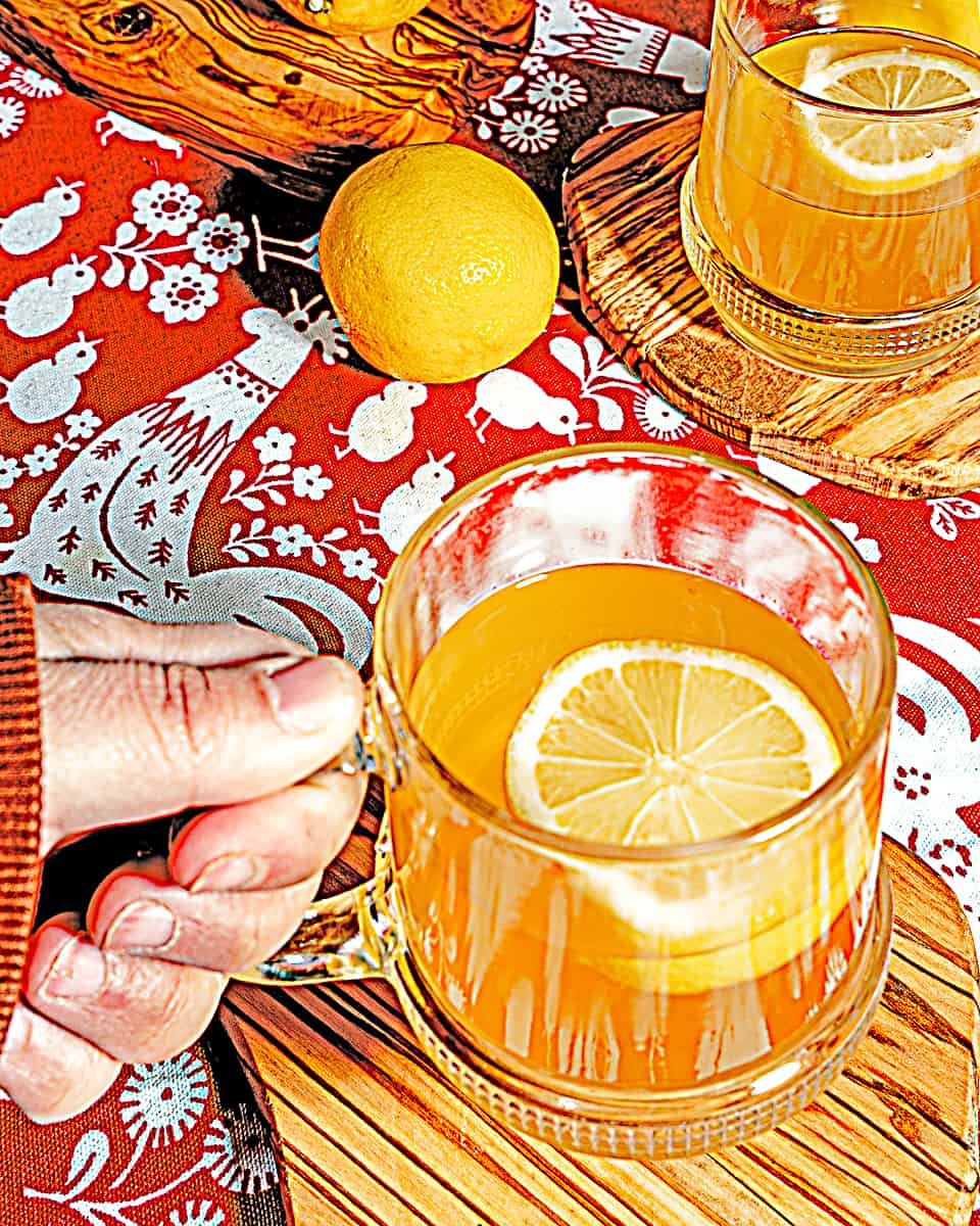 person holding a hot toddy with vodka and lemon honey