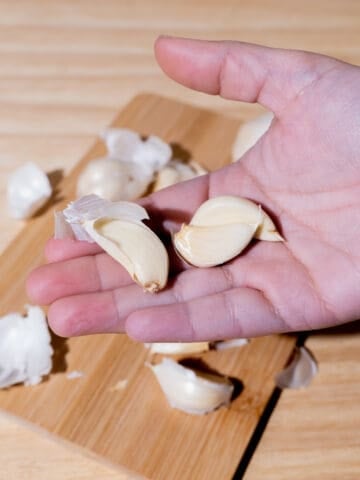 person holding three garlic cloves