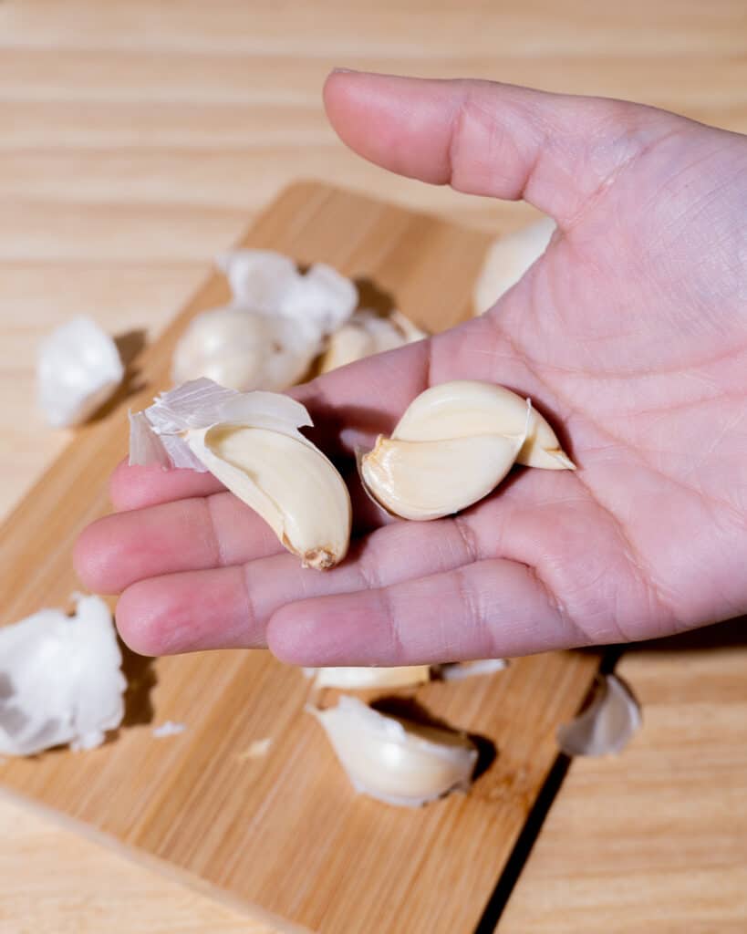 person holding three garlic cloves