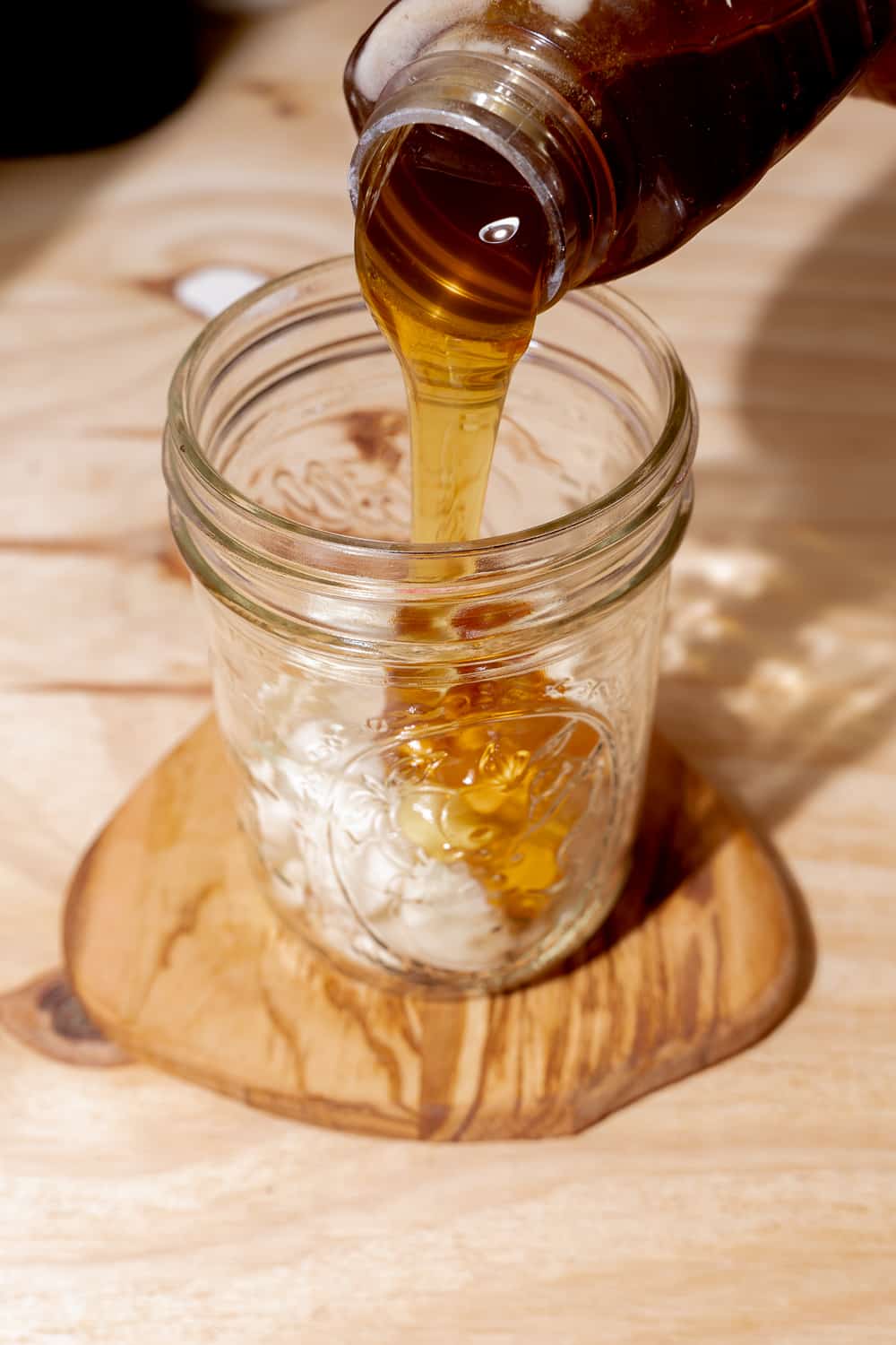 person pouring raw honey over garlic cloves