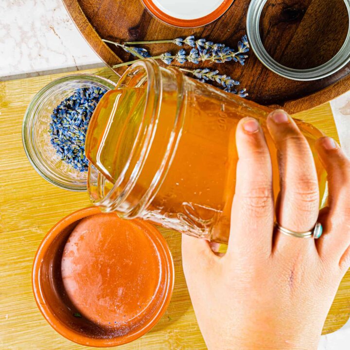 person pouring raw honey on to dried lavender flowers in a mason jar