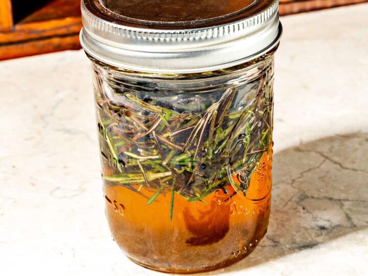 eight oz mason jar of honey with rosemary leaves