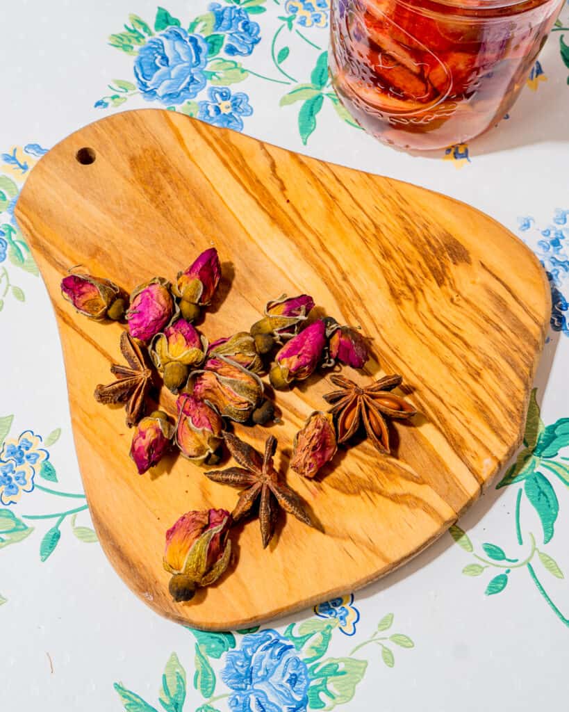 small wooden tray with small rose buds and star anise on them.