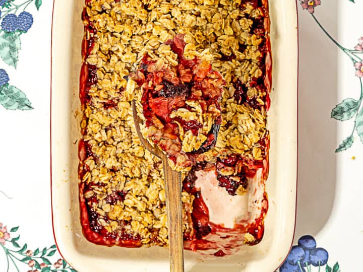 person holding serving spoon with rhubarb crisp