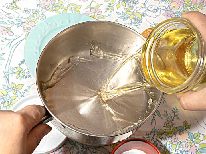 person pouring vinegar into small pot