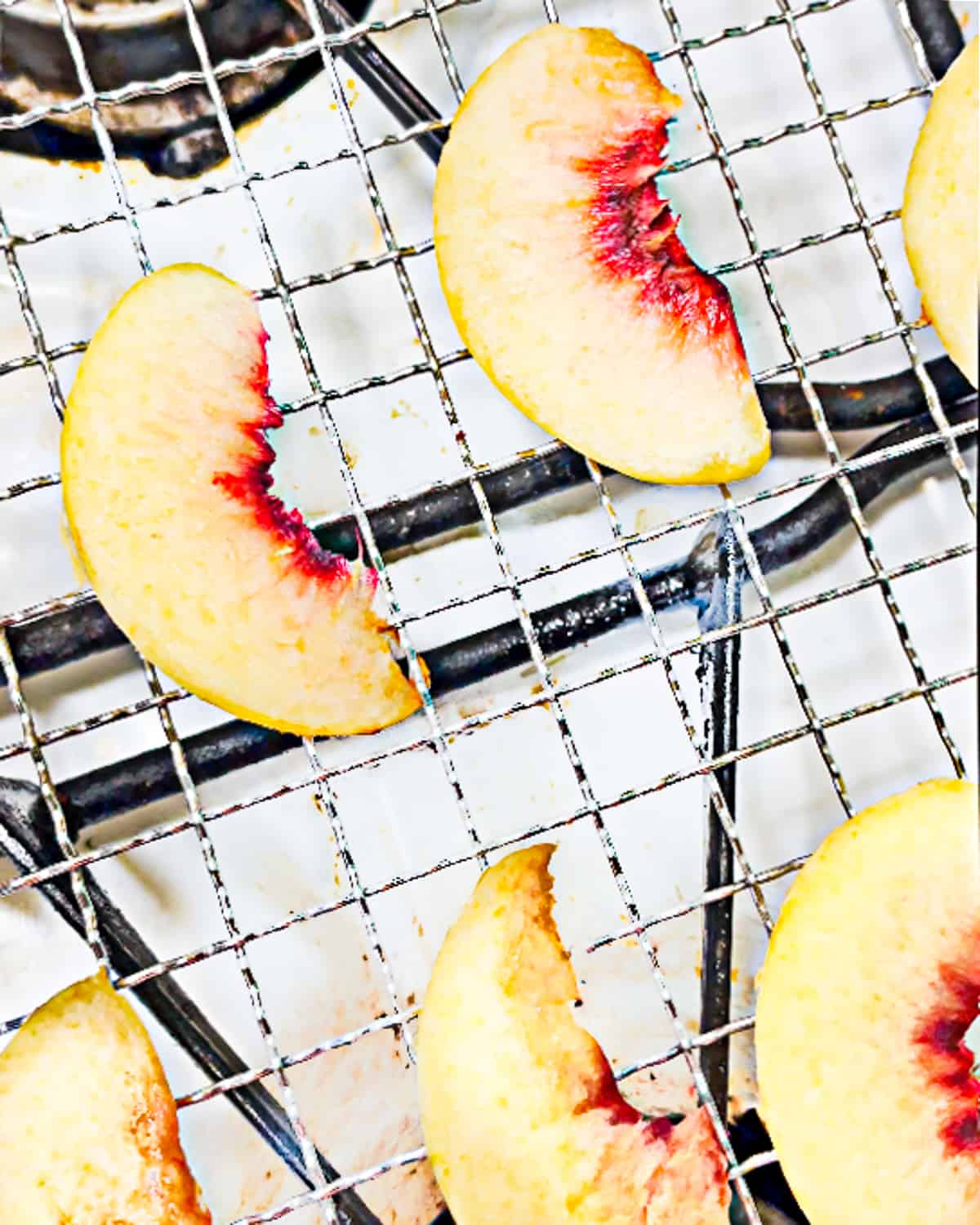 peach slices on a metal rack on a one. 