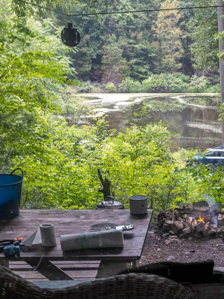 view outside window of hunting cabin: lake, picnic table, camp fire,