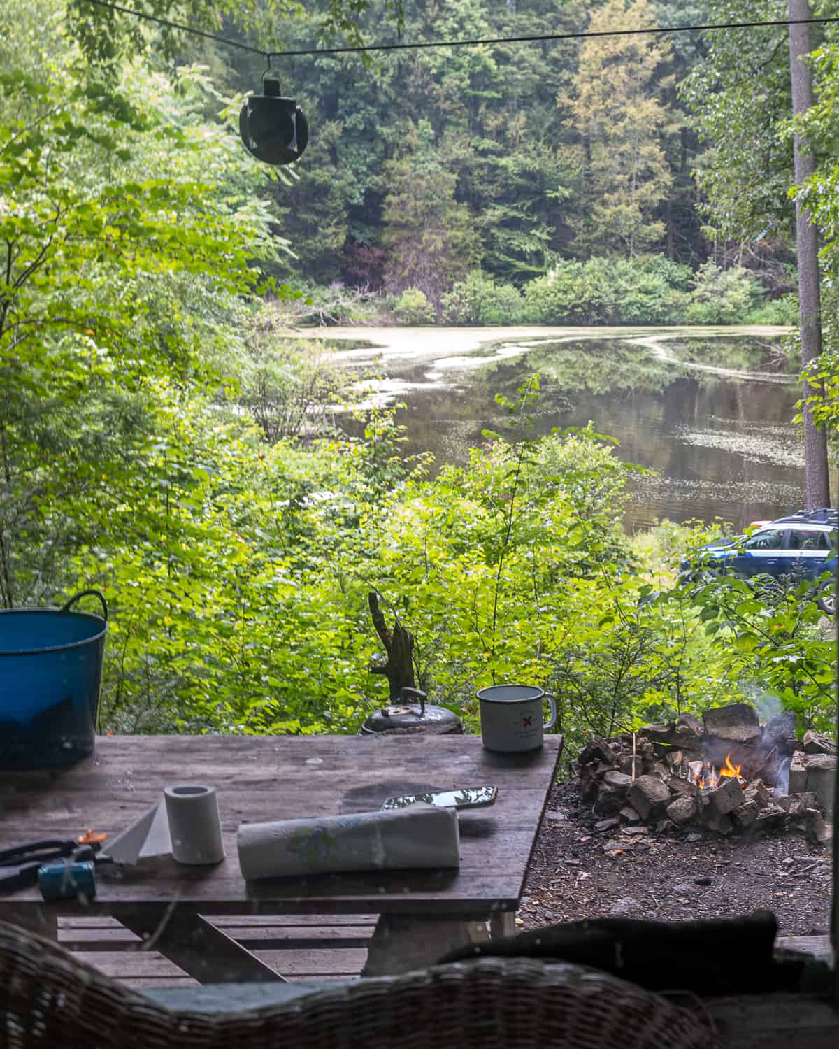 view outside window of hunting cabin: lake, picnic table, camp fire,