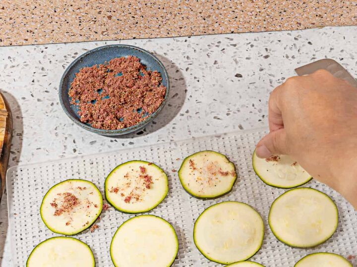 person adding sumac on to zucchini slices