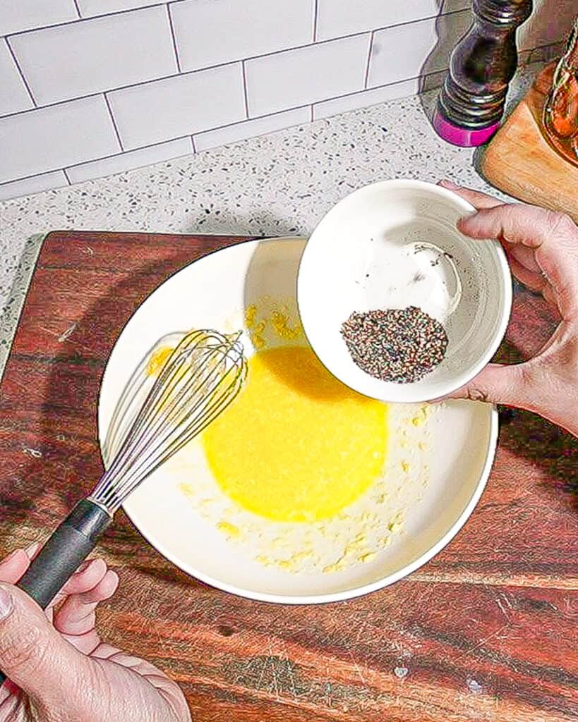 person adding black pepper to carbonara sauce