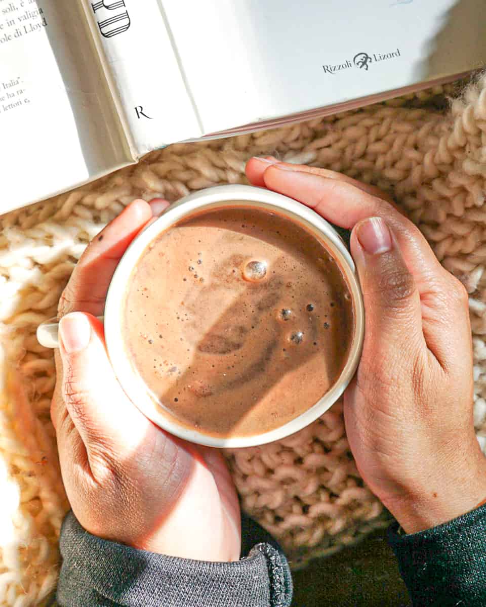 person holding mug of hot chocolate with both hands