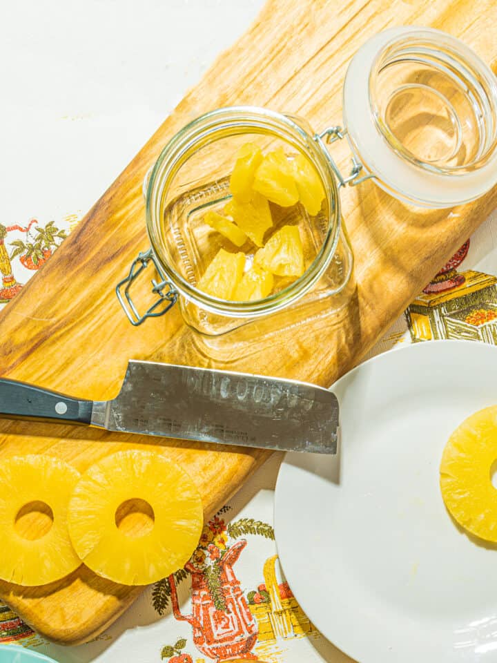chopped pineapple chunks in a glass jar with pineapple rings and a zwilling mini-cleaver
