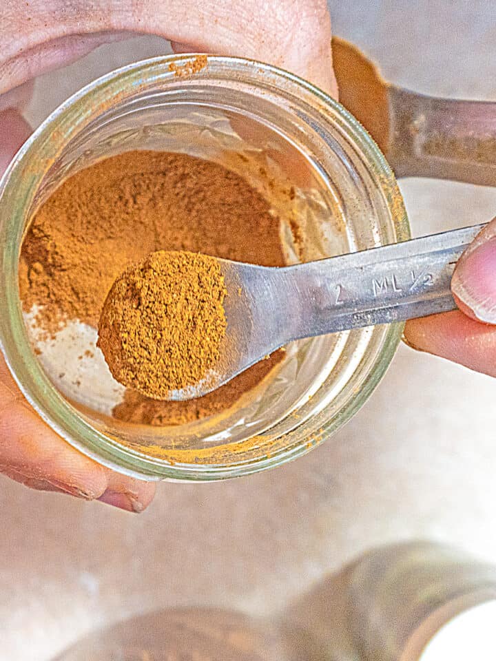 person scooping out pumpkin pie spice out of a mason jar