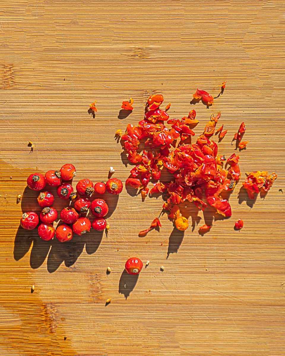 whole red rose hips and peeled rose hips ready for drying
