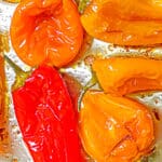 roasted mini peppers on a metal sheet tray in oil