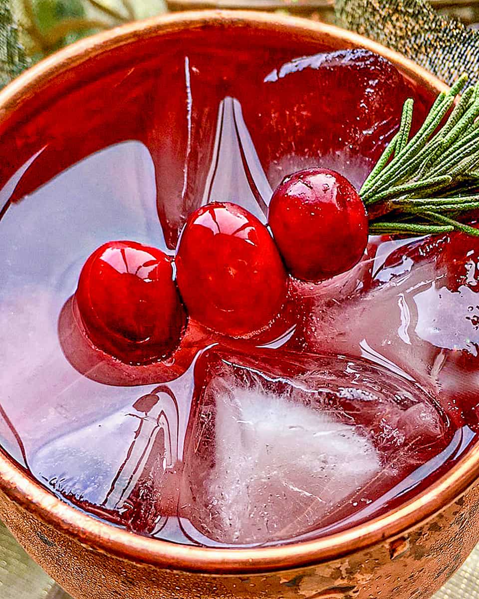 closeup of cranberry mule and cranberries on a sprig of rosemary