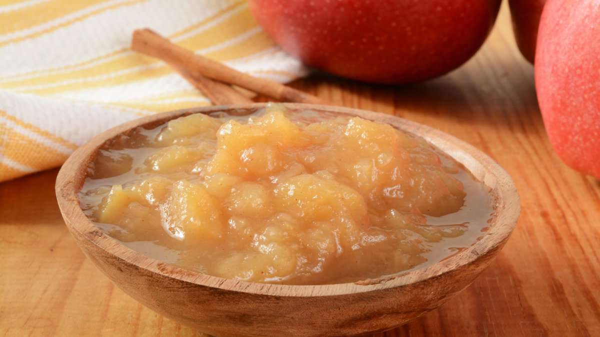 wooden bowl of applesauce on a wood surface