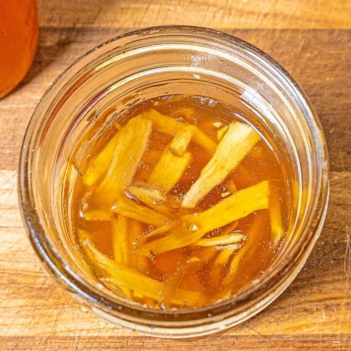 top down view of slices of ginger in a small jar of honey