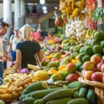 blonde person in a farmers market surrounded by colorful produce in madeira