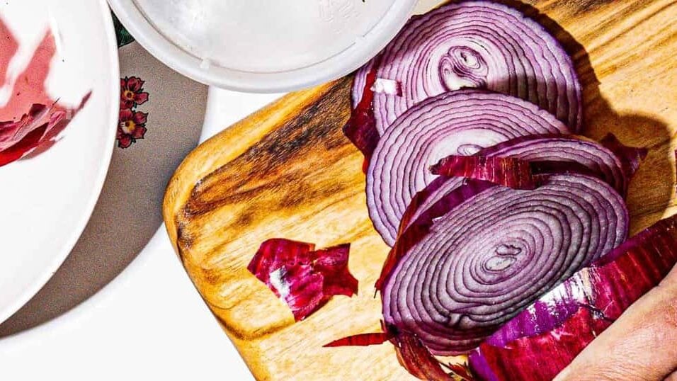left handed person slicing red onion