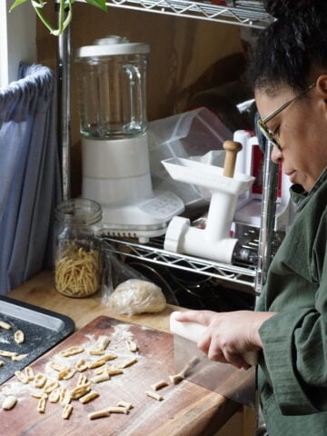 person cutting strings of rolled out pasta