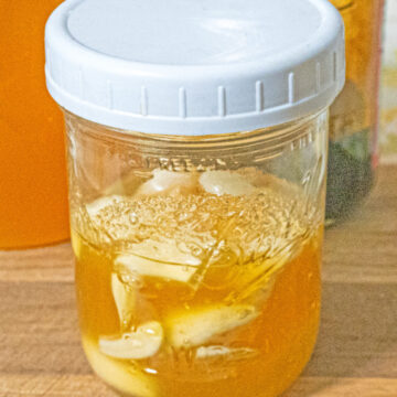 mason jar of garlic honey ferment on a wooden cutting board