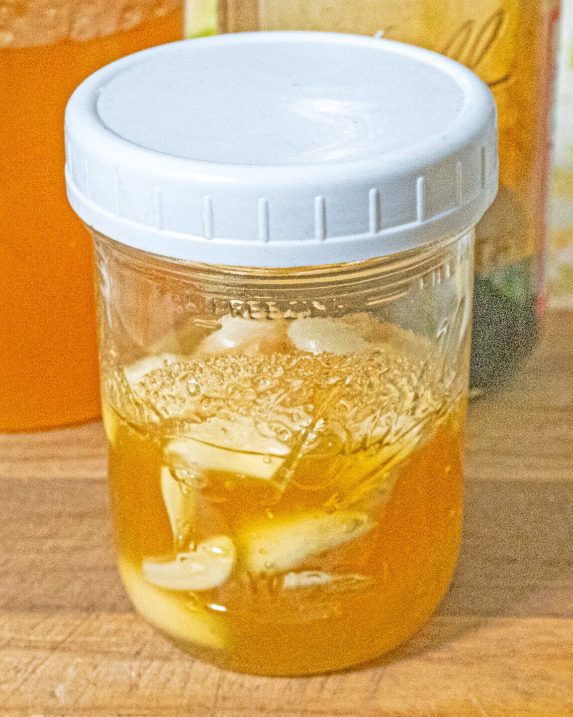 mason jar of garlic honey ferment on a wooden cutting board