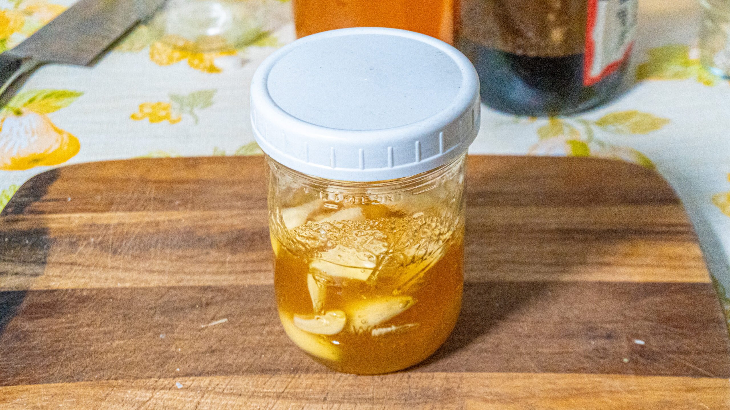 mason jar of garlic honey ferment on a wooden cutting board