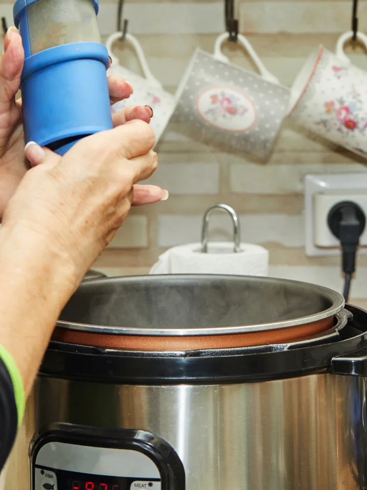 Cooking meat in a slow cooker, a woman peppers the meat