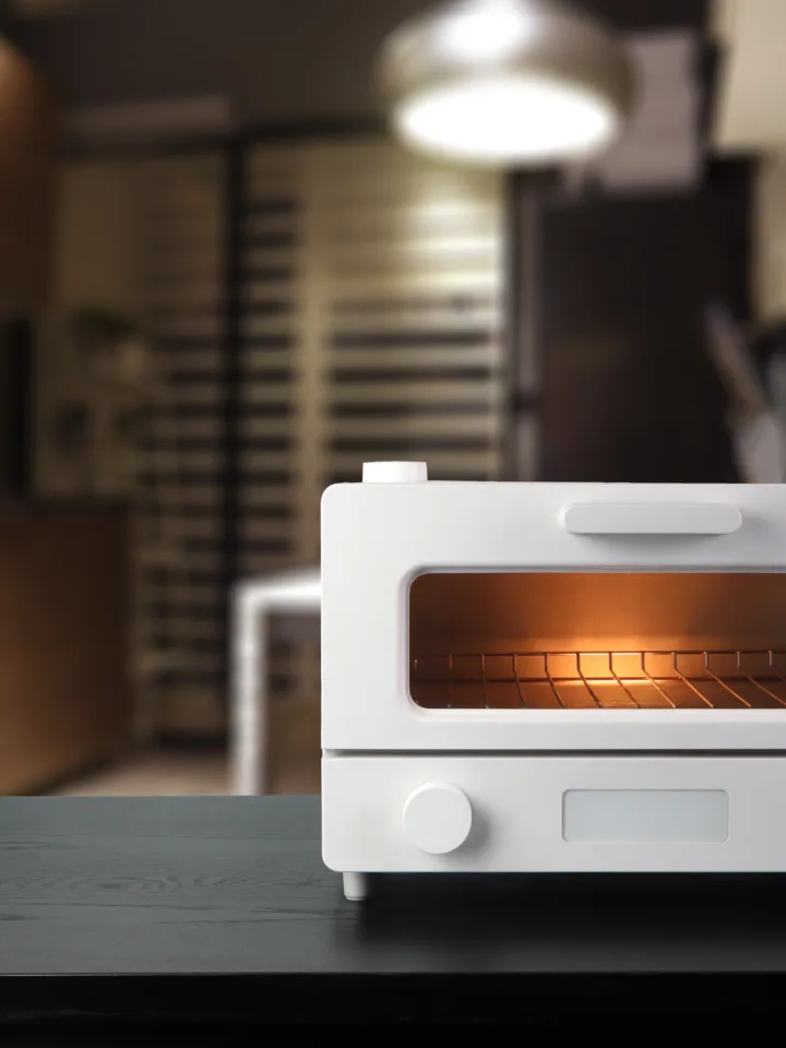 White modern design toaster oven is on the brown wooden table with background of nice dinner kitchen room during breakfast