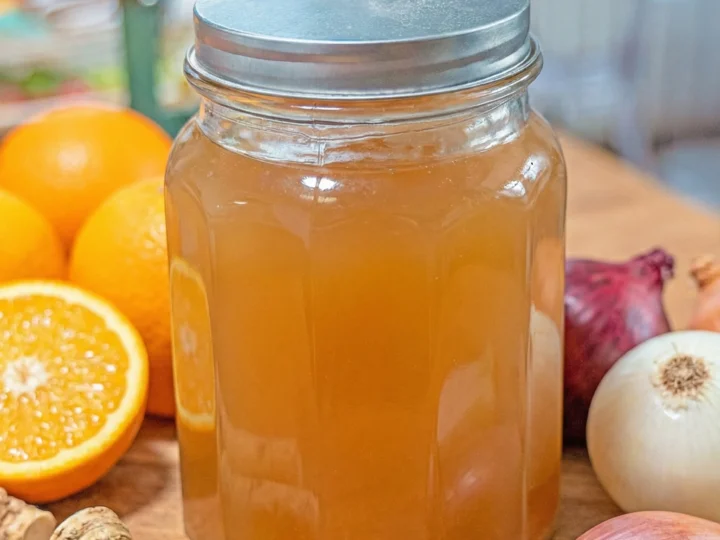jar of fire cider with oranges, horseradishes and onions around it