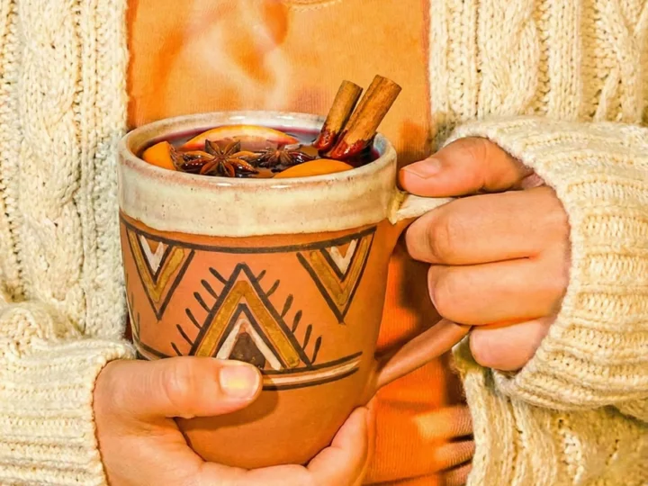 person in w white sweater holding a mug of mulled wine